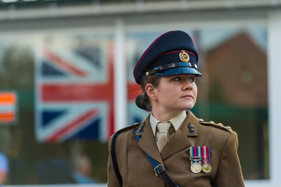 E An officer from the Headquarters of 49 (East) Brigade stands against one of the many Union Flags on show.
